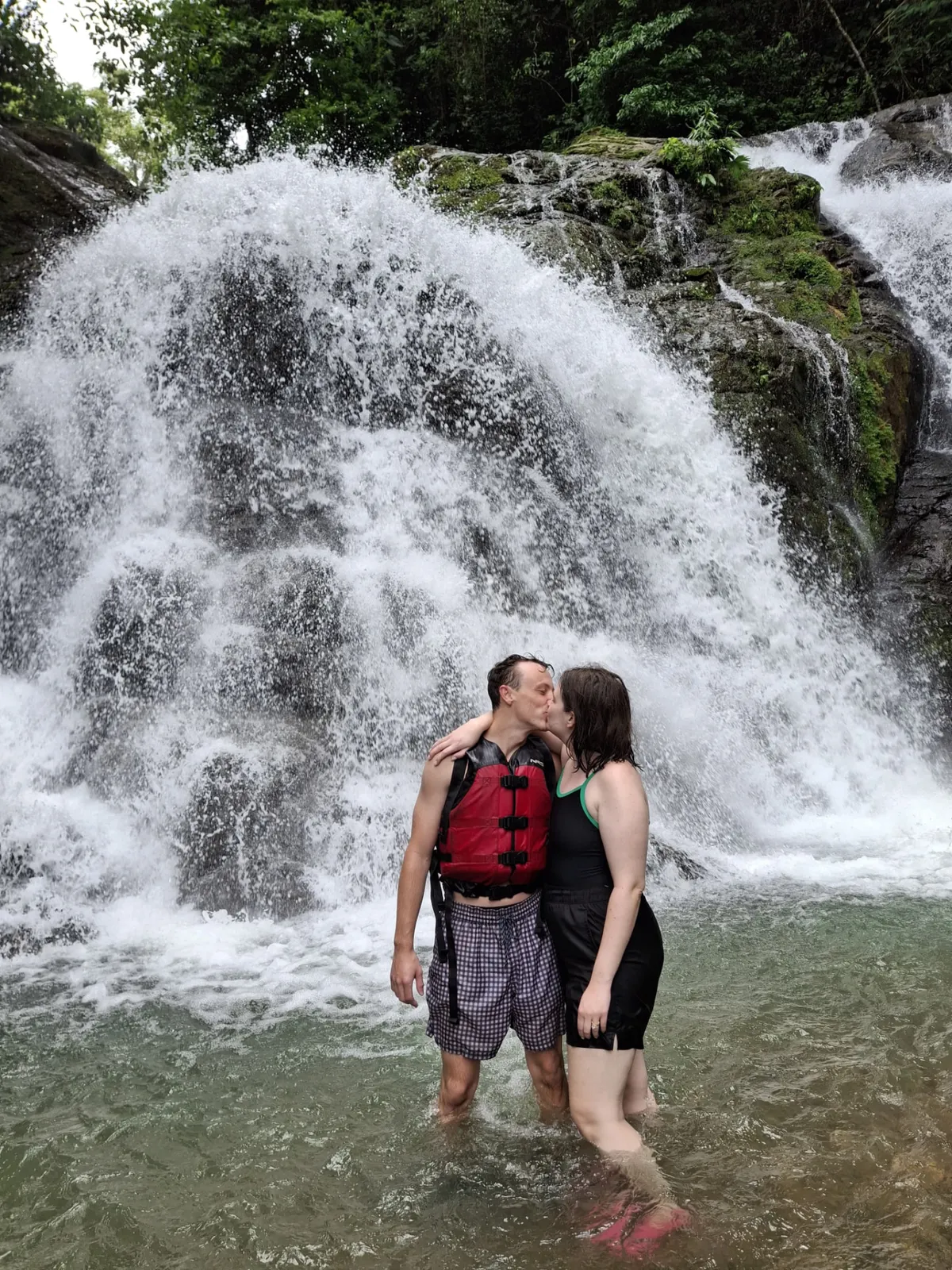 Happy couple kissing under a jungle waterfall during the Savegre rafting tour
